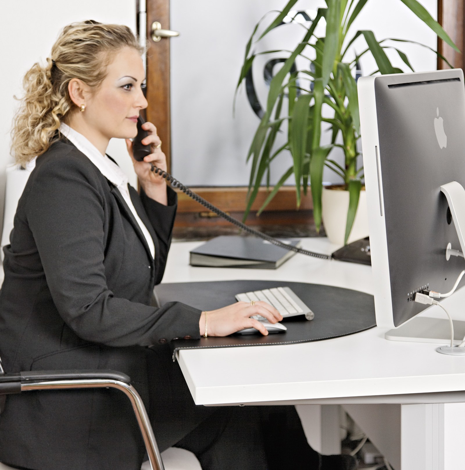 Mitarbeiterin im Büro telefoniert und arbeitet am Computer